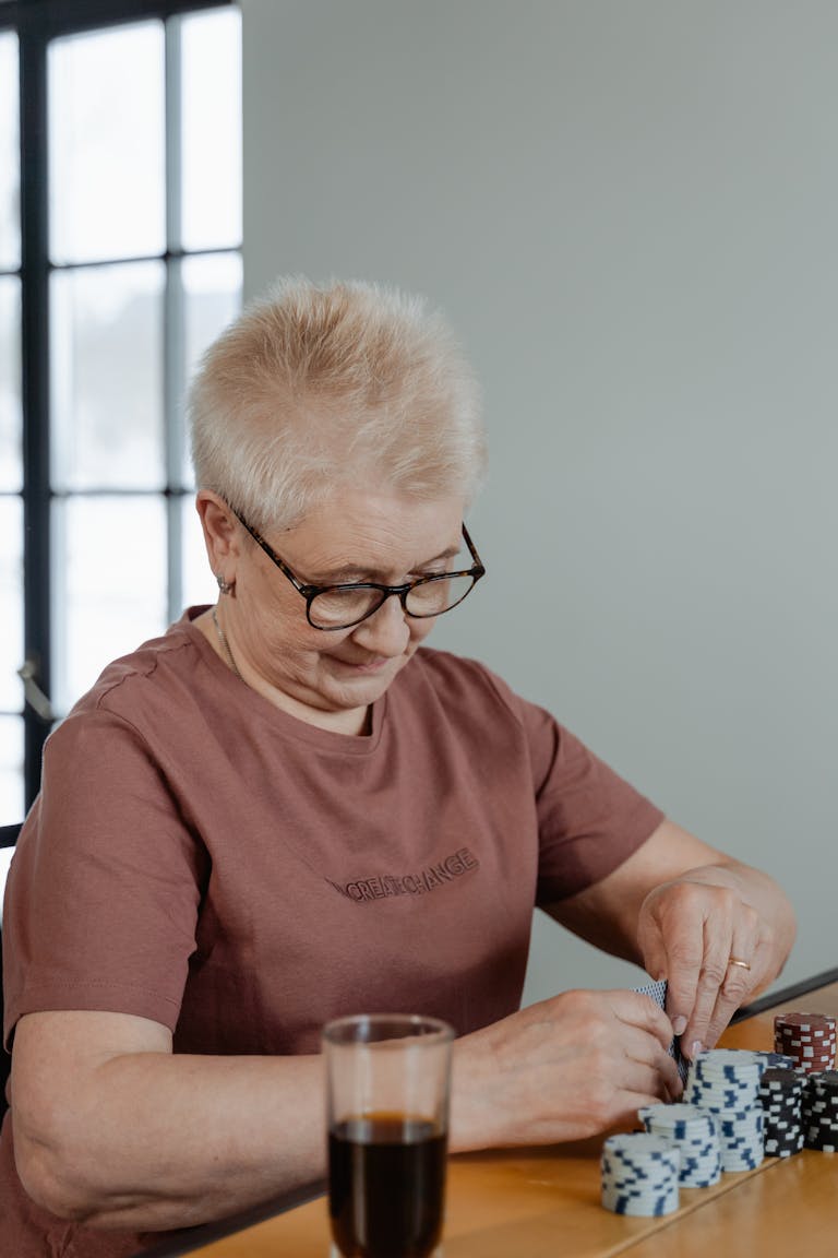 A senior woman enjoying a poker game at home, stacking chips with focus.