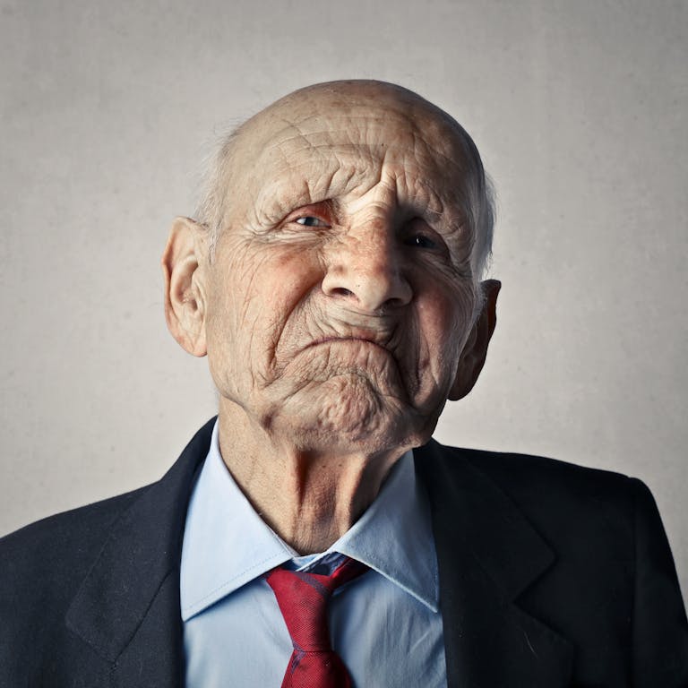 Close-up portrait of a thoughtful elderly man in a suit, expressing a serious mood.