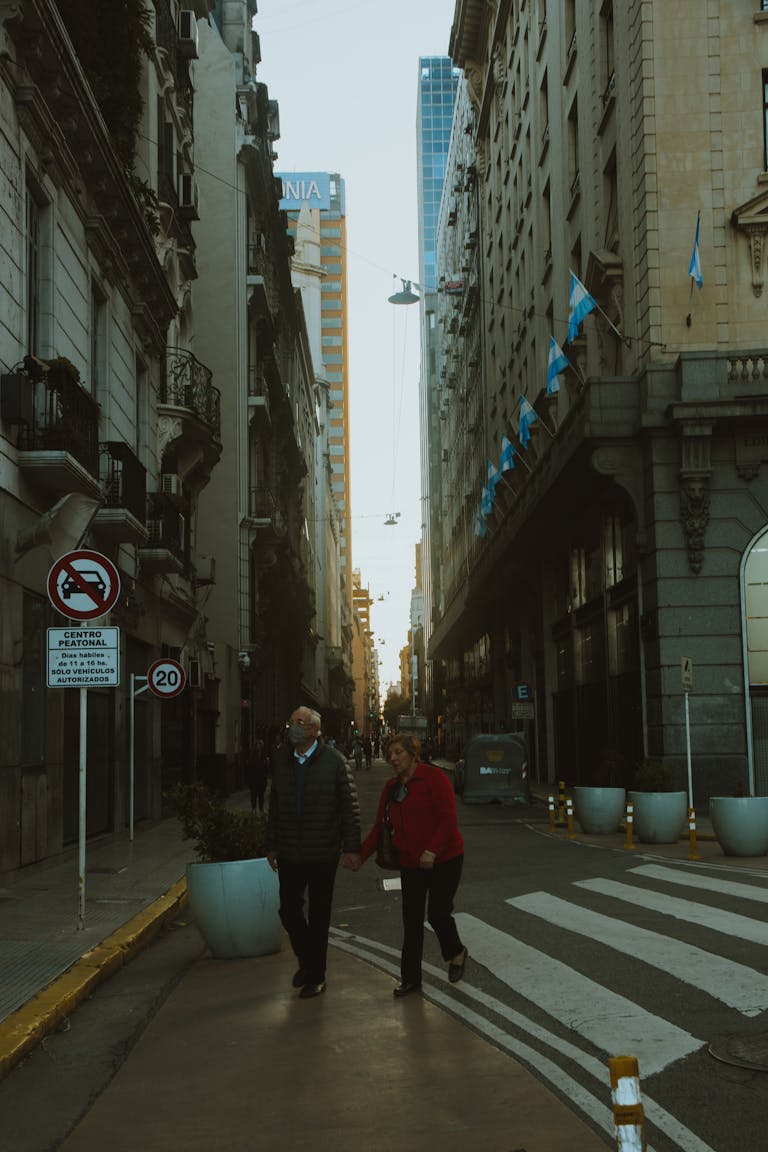 Elderly couple walking hand in hand on a city street in Buenos Aires, Argentina during daytime.
